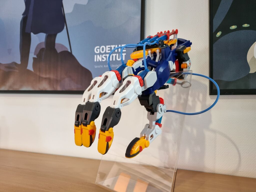 A colorful, plastic model of a cyborg's hand for education on the operation of hydraulic mechanisms.