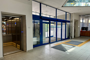 Im Hauptgebäude der Bibliothek – Blick auf den Haupteingang mit Schiebetüren und Aufzügen daneben.